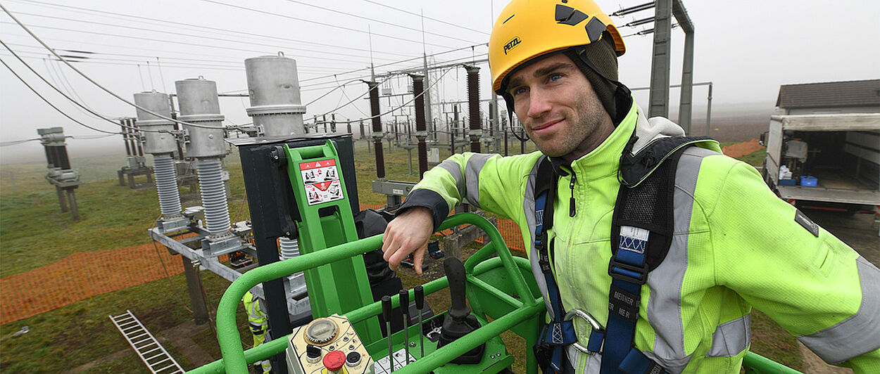 Monteur in Schutzausrüstung bei Arbeiten an Umspann- und Stromnetzanlage