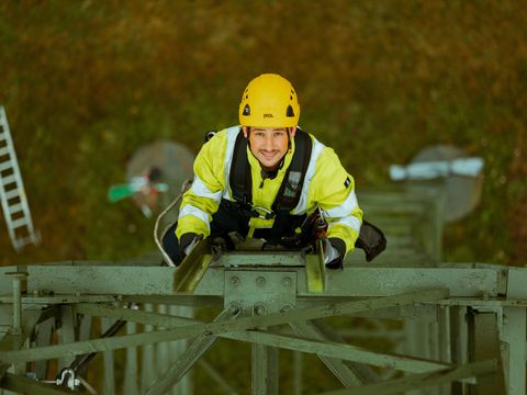 Arbeiter hoch oben auf einem Strommast bei der Arbeit